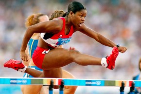 Perdita Felicien élance une jambe vers l'avant alors qu'elle saute à toute vitesse un obstacle à l'épreuve du 100 mètres haies féminin en athlétisme à Athènes 2004.