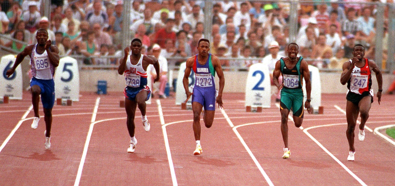 Cinq athlètes masculins courent sur la piste d'athlétisme.
