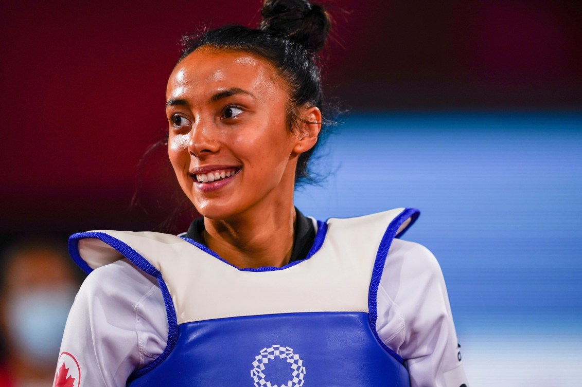 Une athlète de taekwondo sourit en regardant vers la gauche.