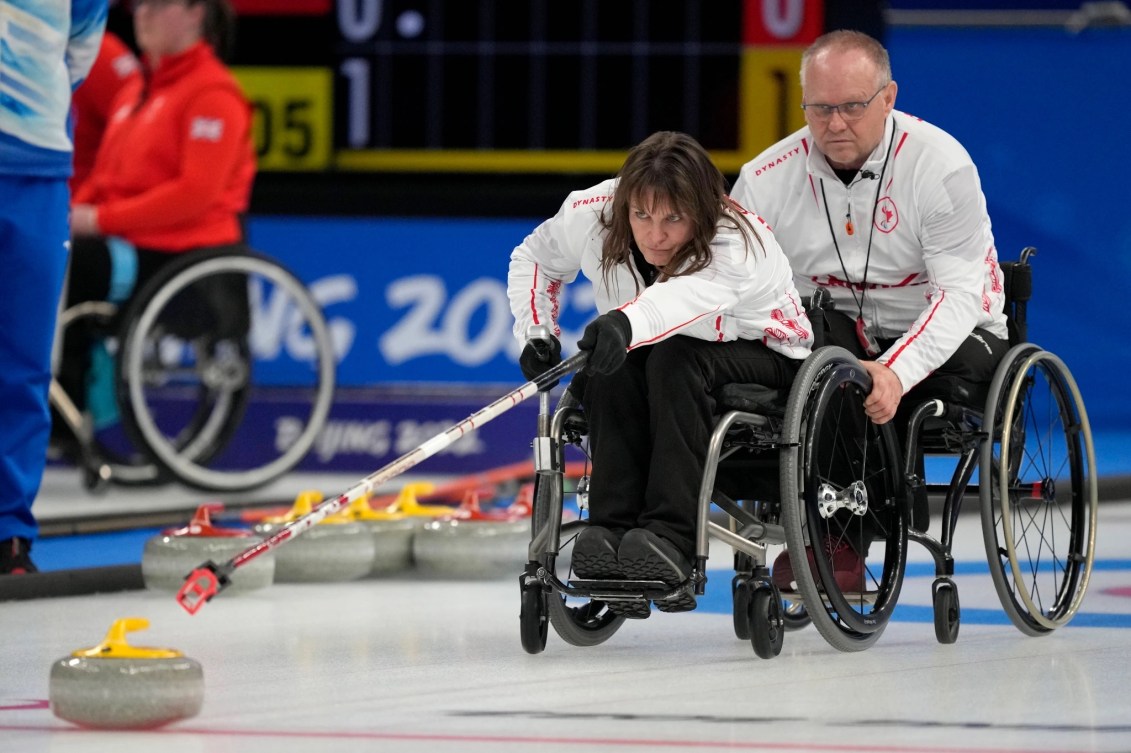 Une joueuse de curling en fauteuil roulant sur la surface de jeu. 
