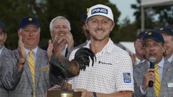 Mackenzie Hughes tient le trophée en forme de coq.