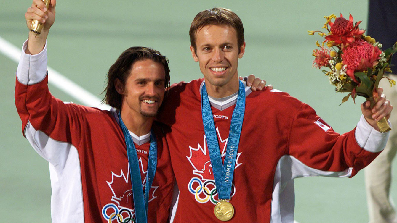 Sébastien Lareau et Daniel Nestor posent avec leur médaille d'or olympique au cou sur le terrain de tennis.