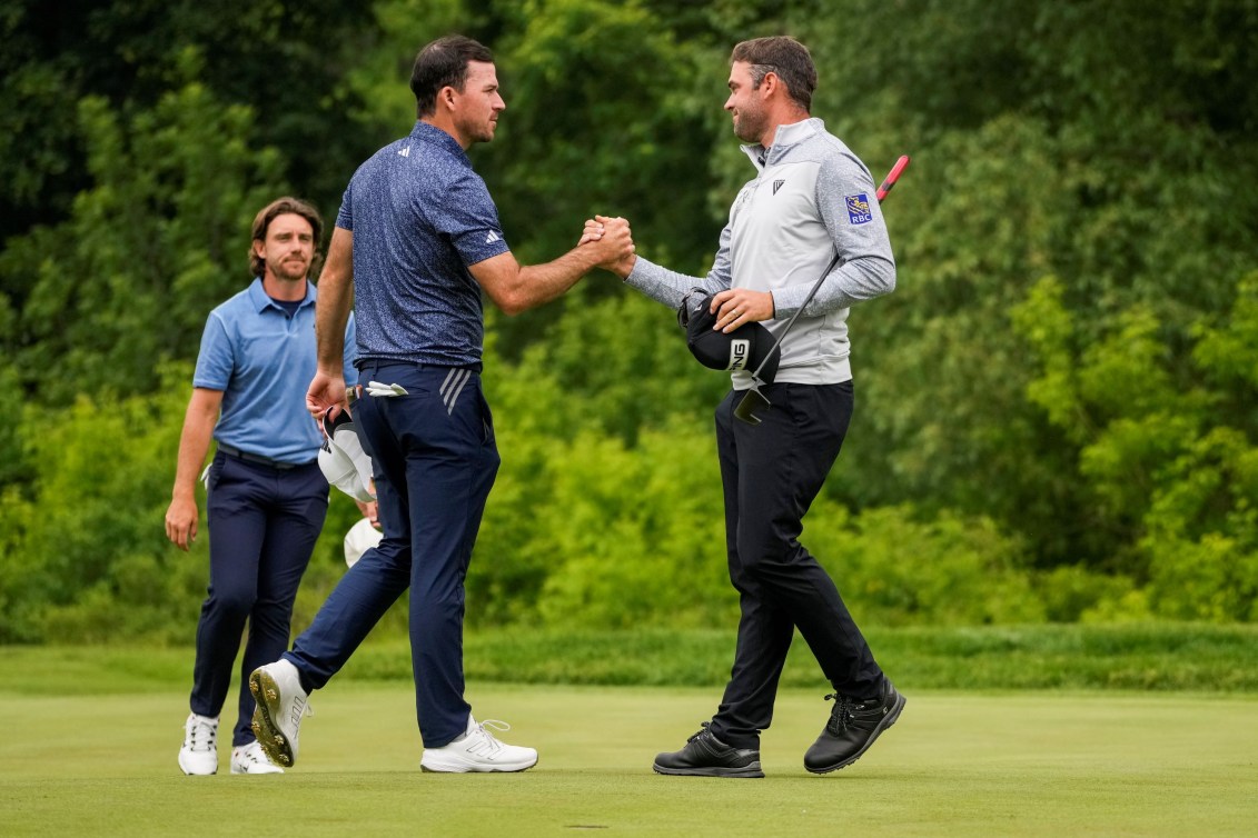 Corey Conners et Nick Taylor se serrent la main sur un terrain de golf