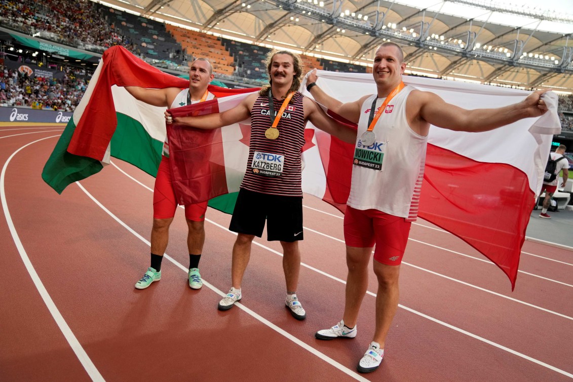 De gauche à droite, le médaillé de bronze Bence Halasz de Hongrie, le médaillé d'or Ethan Katzberg du Canada et le médaillé d'argent Wojciech Nowicki de Pologne posent avec leur médaille et le drapeau de leur pays.