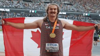 Ethan Katzberg avec sa médaille d'or au cou et tenant le drapeau canadien.