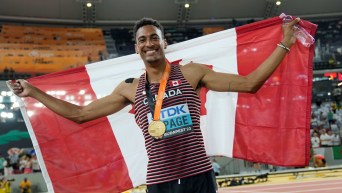 Pierce LePage tient le drapeau du Canada derrière lui. Il a sa médaille d'or autour du cou.
