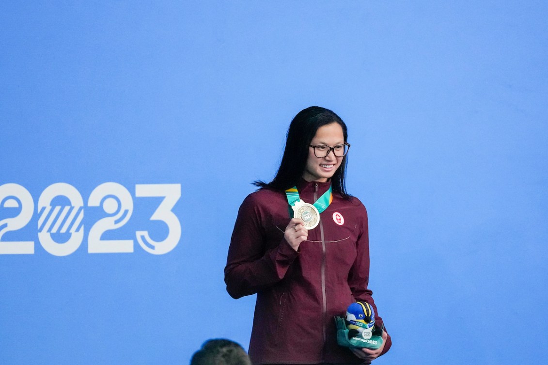 Maggie Mac Neil pose pour une photo avec sa médaille dans sa main droite.