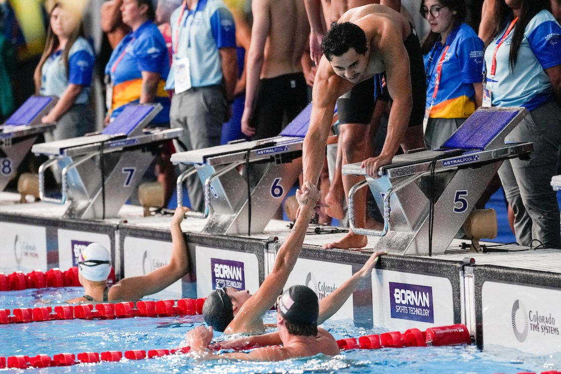 Javier Acevedo, penché vers la piscine, sert la main de sa coéquipière Mary-Sophie Harvey