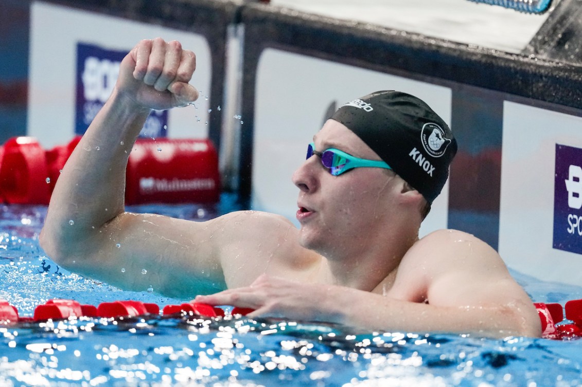 Finlay Knox lève le bras dans les airs dans la piscine. 