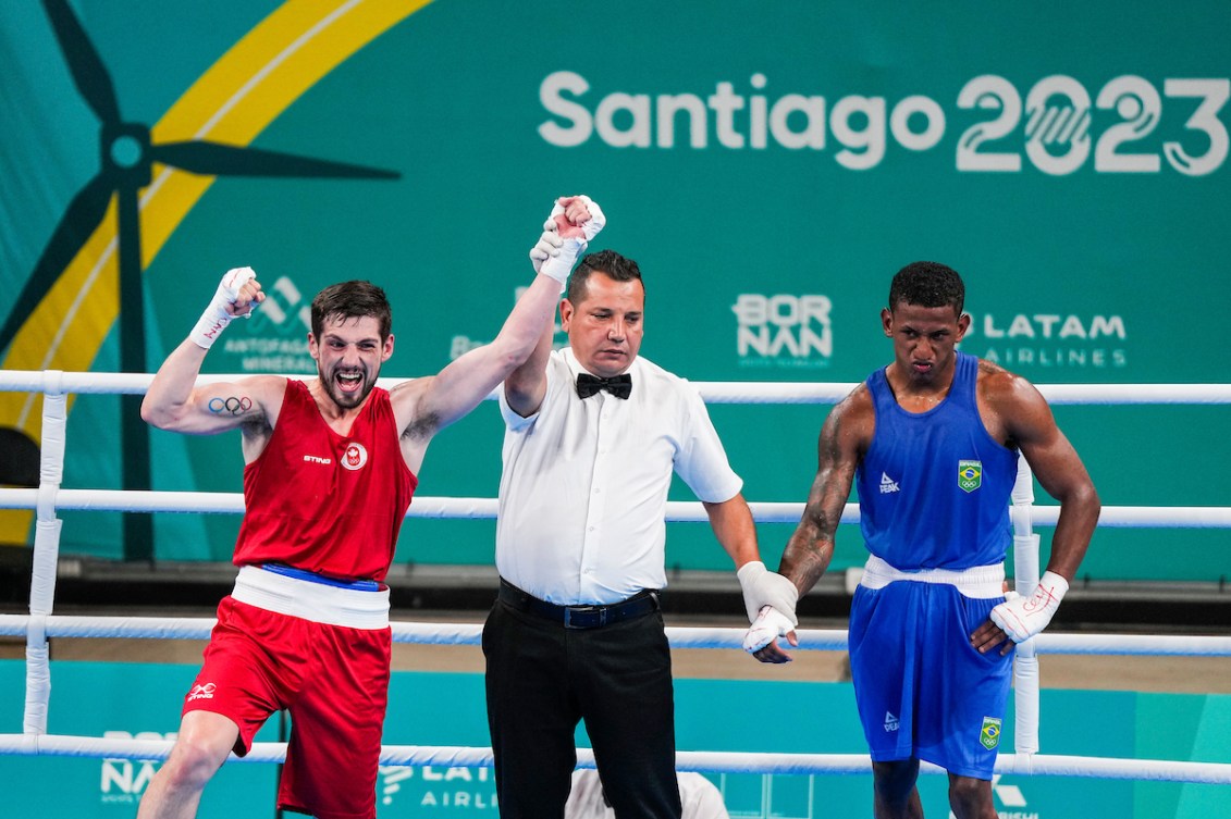 Wyatt Sanford, l'arbitre et le boxeur brésilien après le combat. Sanford lève les bras dans les airs.