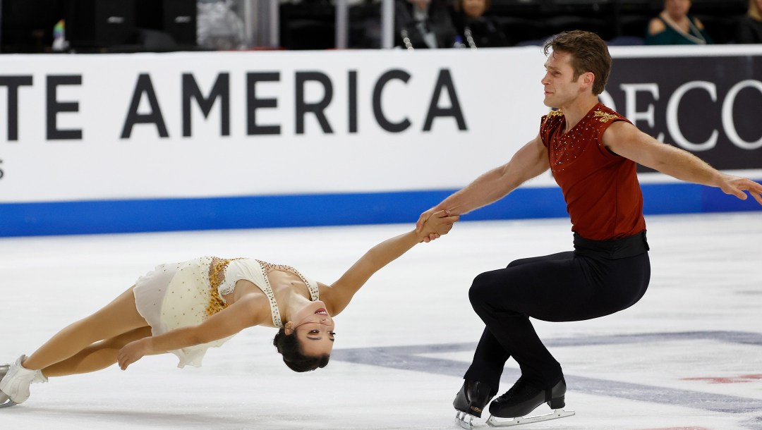 Un couple de patineurs effectuent une spirale sur la glace.