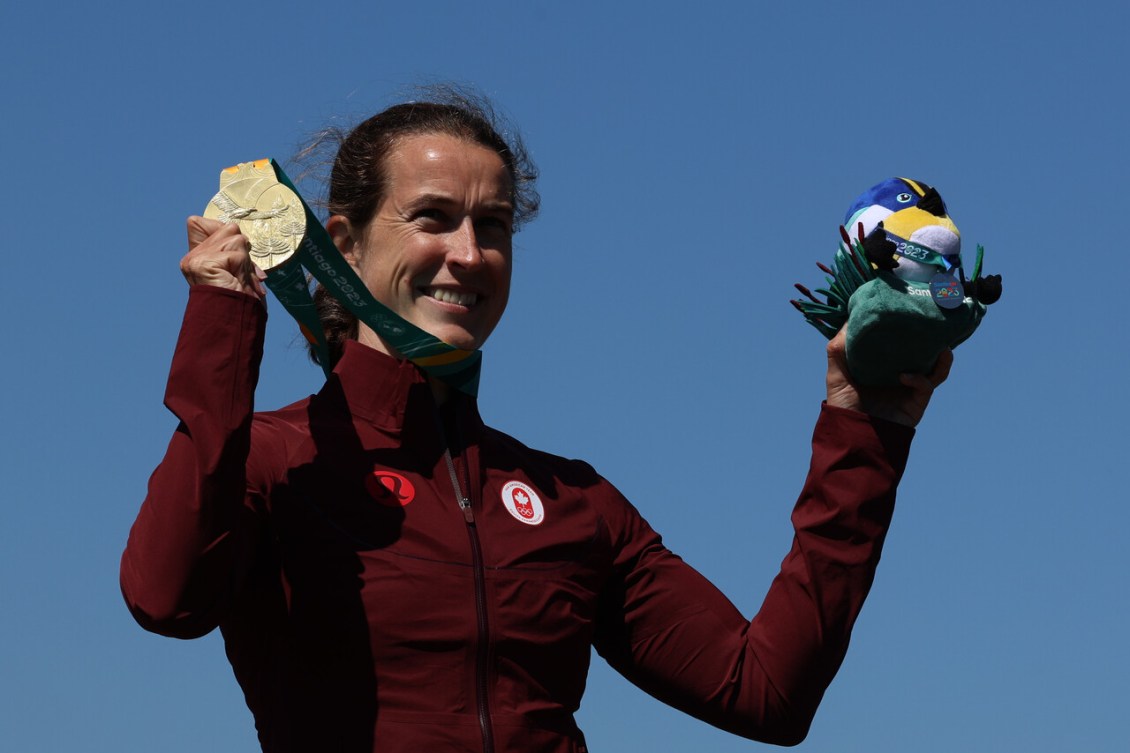 Michelle Russell, souriante, montre sa médaille qu'elle a accroché à son cou