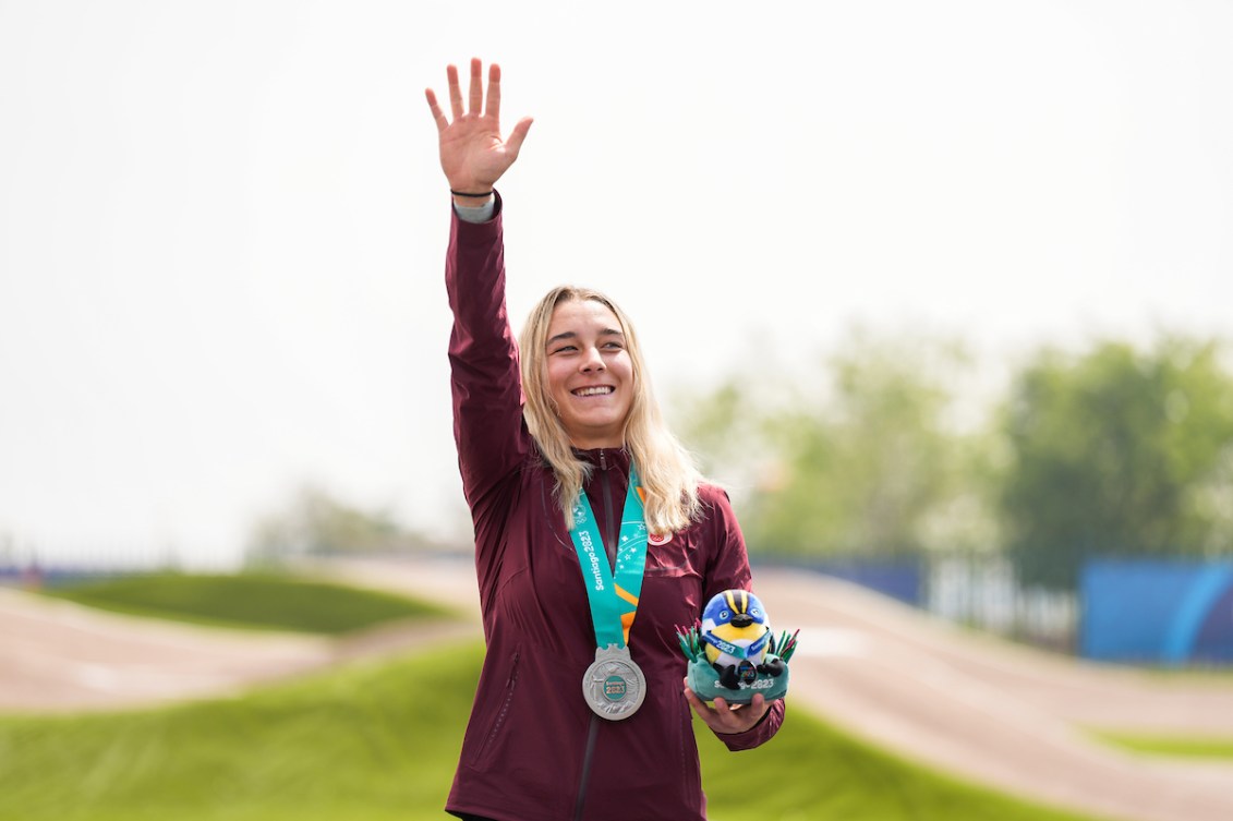 Molly Simpson lève un bras avec une médaille autour du cou et une peluche dans l'autre main. 