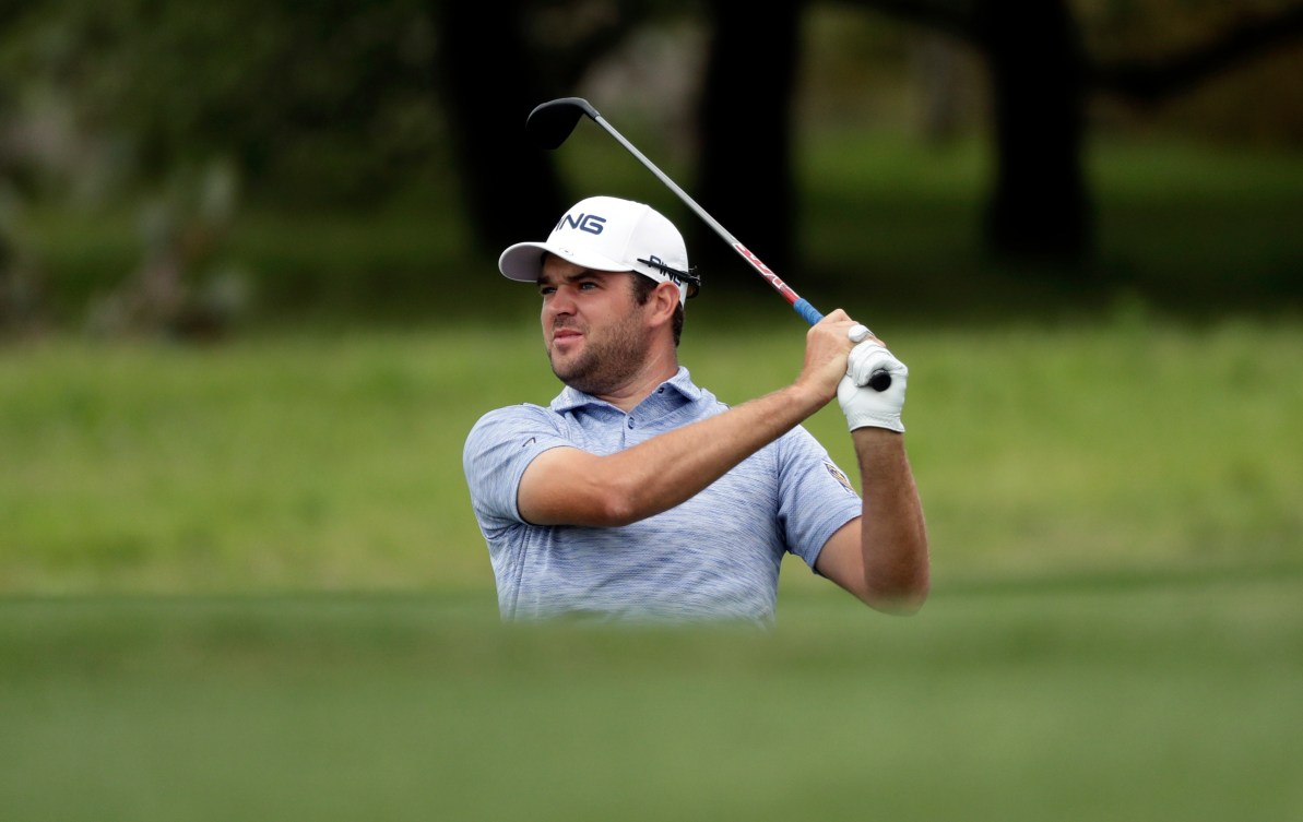 Corey Conners sur le terrain de golf regarde sa balle au loin. 