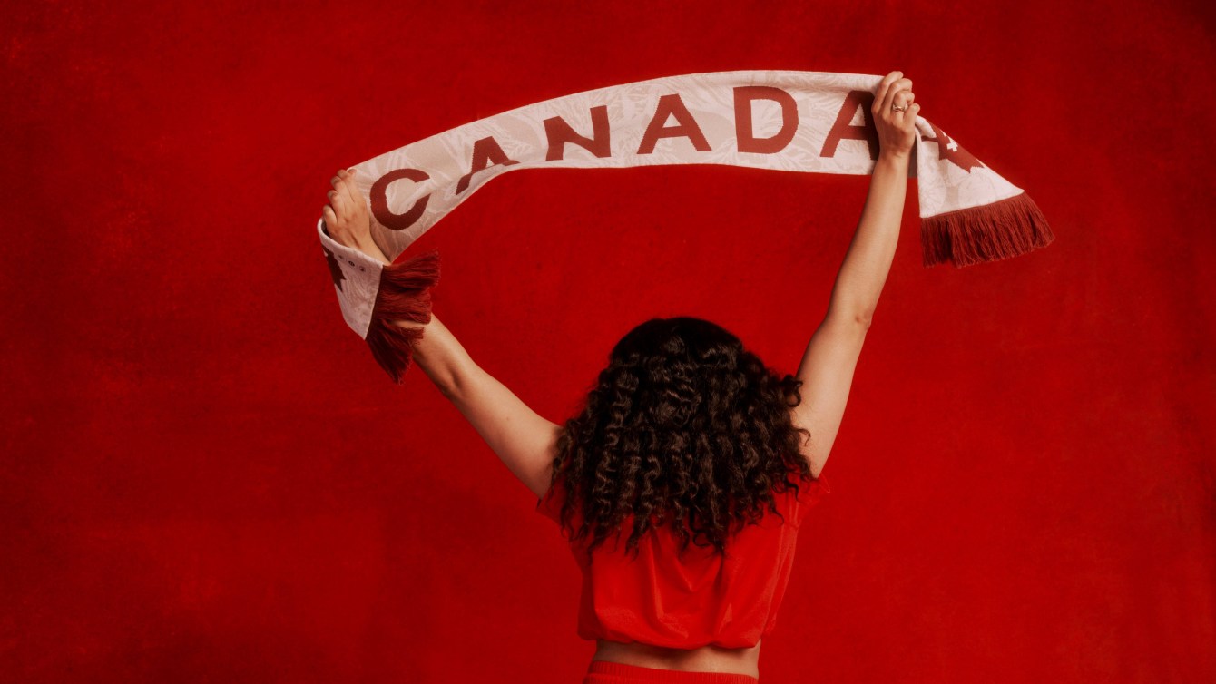 Une personne tient une écharpe sur laquelle il est écrit Canada.
