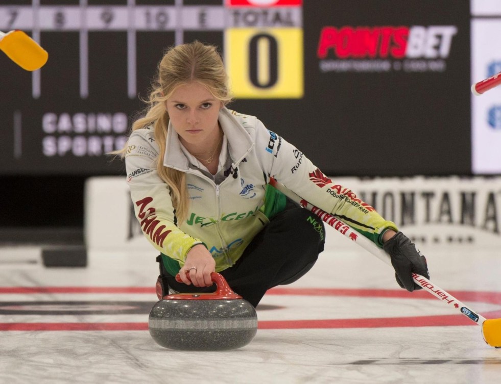 Une joueuse de curling lance une pierre.