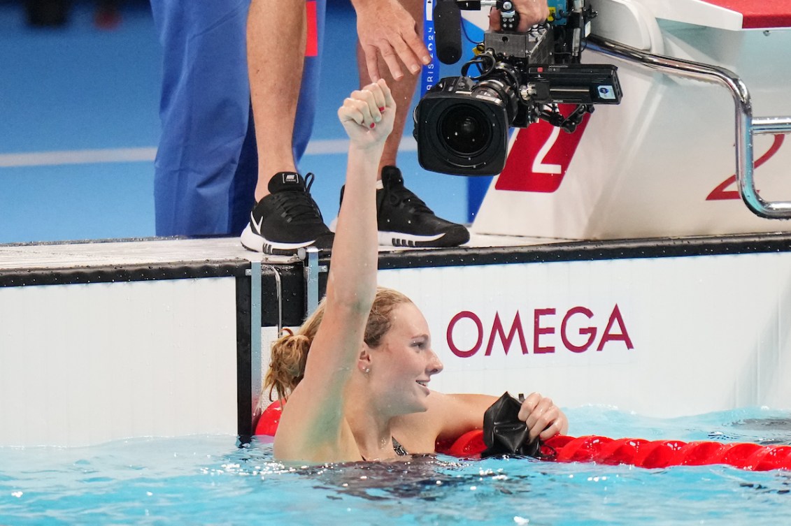 Summer McIntosh  dans la piscine après sa course lève le bras dans les airs.