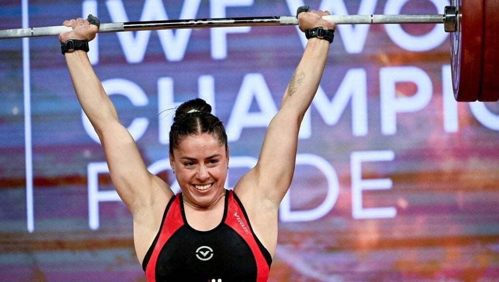 Maude Charron smiles while lifting barbell above her head