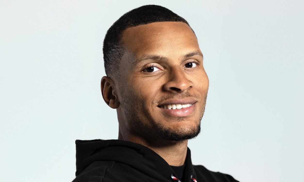 André De Grasse, sur fond blanc, souriant et regardant droit devant lui.