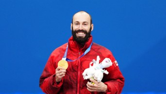 Steven Dubois avec sa médaille d'or dans la main droite et une peluche de la mascotte des Jeux olympiques dans la main gauche.