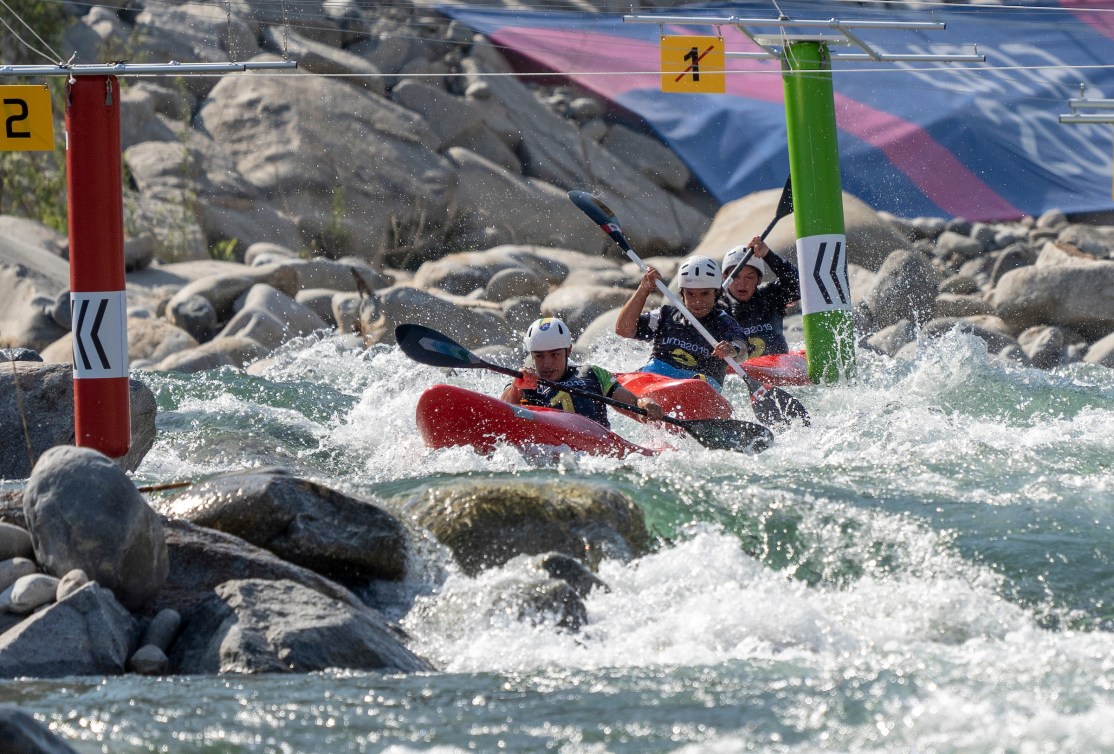 Extreme slalom kayakers paddle through whitewater and rocks 