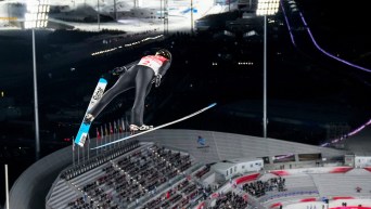 Ski jumper looks down on the stadium from the air with skis extended