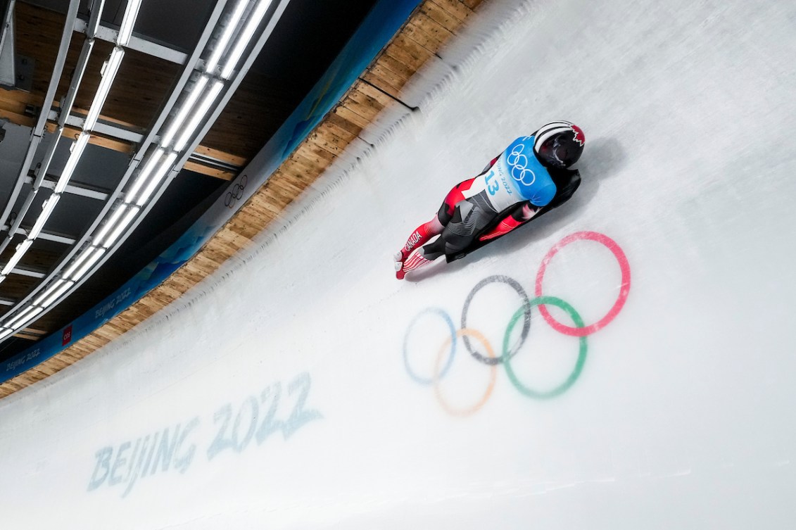 Skeleton racer slides over the Olympic rings on an ice track 