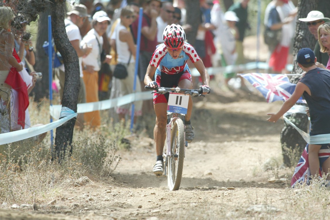 Marie-Helene Premont rides her mountain bike on a dirt trail past spectators 
