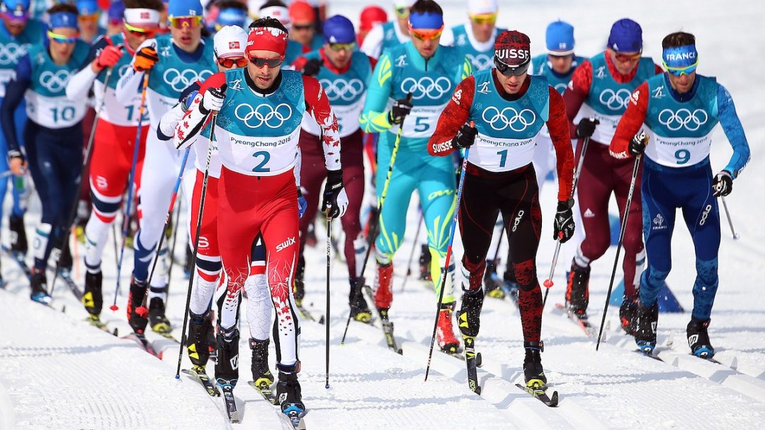 A large group of cross-country skiers compete in a mass start race