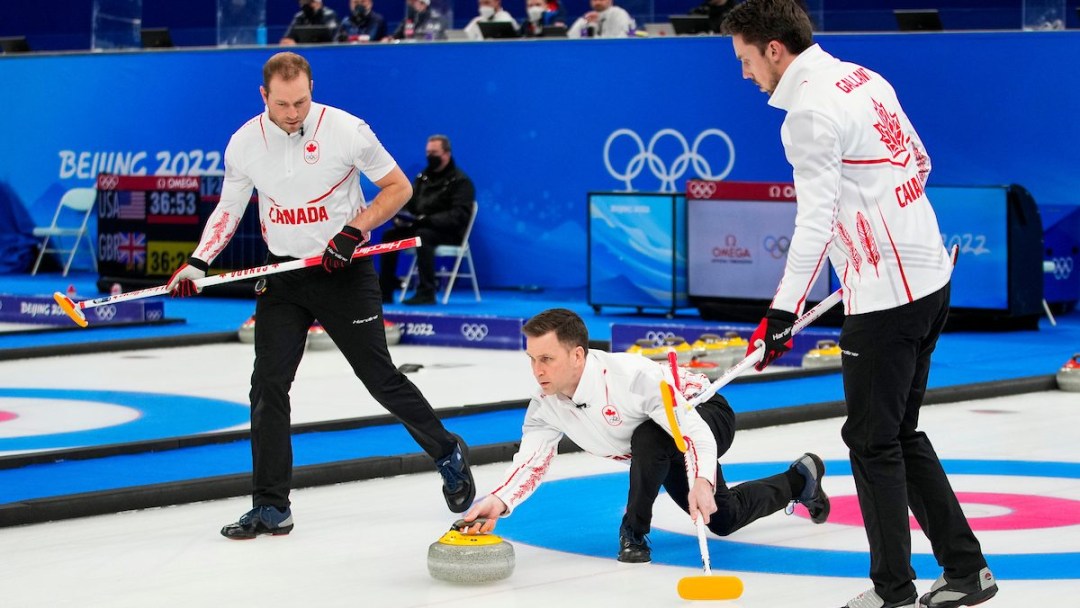 A curler in white jacket and black pants throws a yellow stone that his teammates prepare to sweep