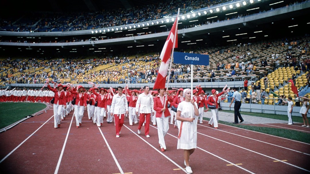 Low shot of Canadian flagbearer leading team into opening ceremony