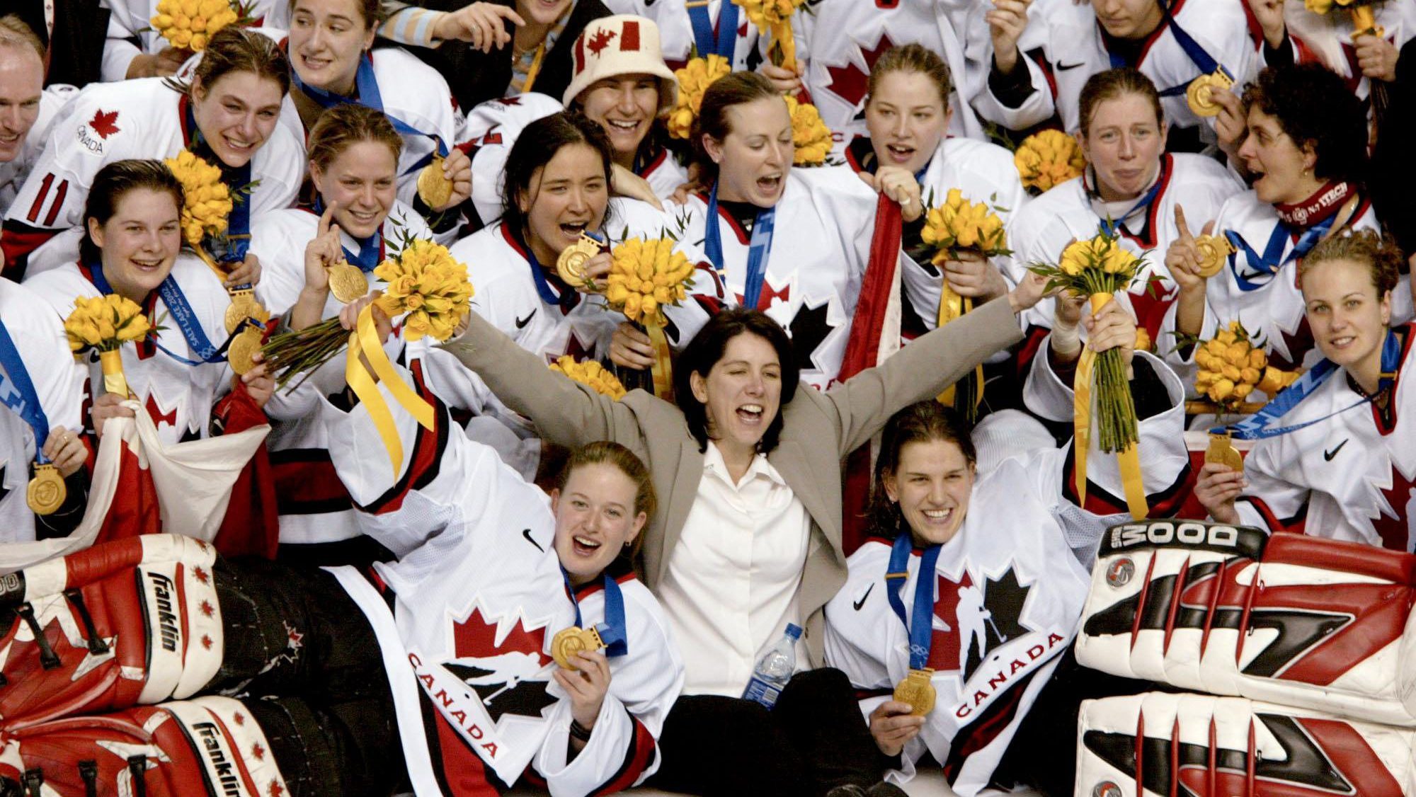 Canadian women's hockey team coach Daniele Sauvageau (centre) and the Canadian women's hockey team pose for a team picture with their gold medal after defeating the United States 3 - 2 in Salt Lake City , Utah during the Winter Olympics, Thursday, Feb. 21, 2002. (CP PHOTO/COC/Mike Ridewood)