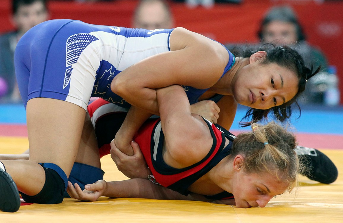 Carol Huynh in blue pins her opponent in red to the wrestling mat 