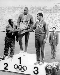 Harry Jerome shakes hands with other medallists on podium