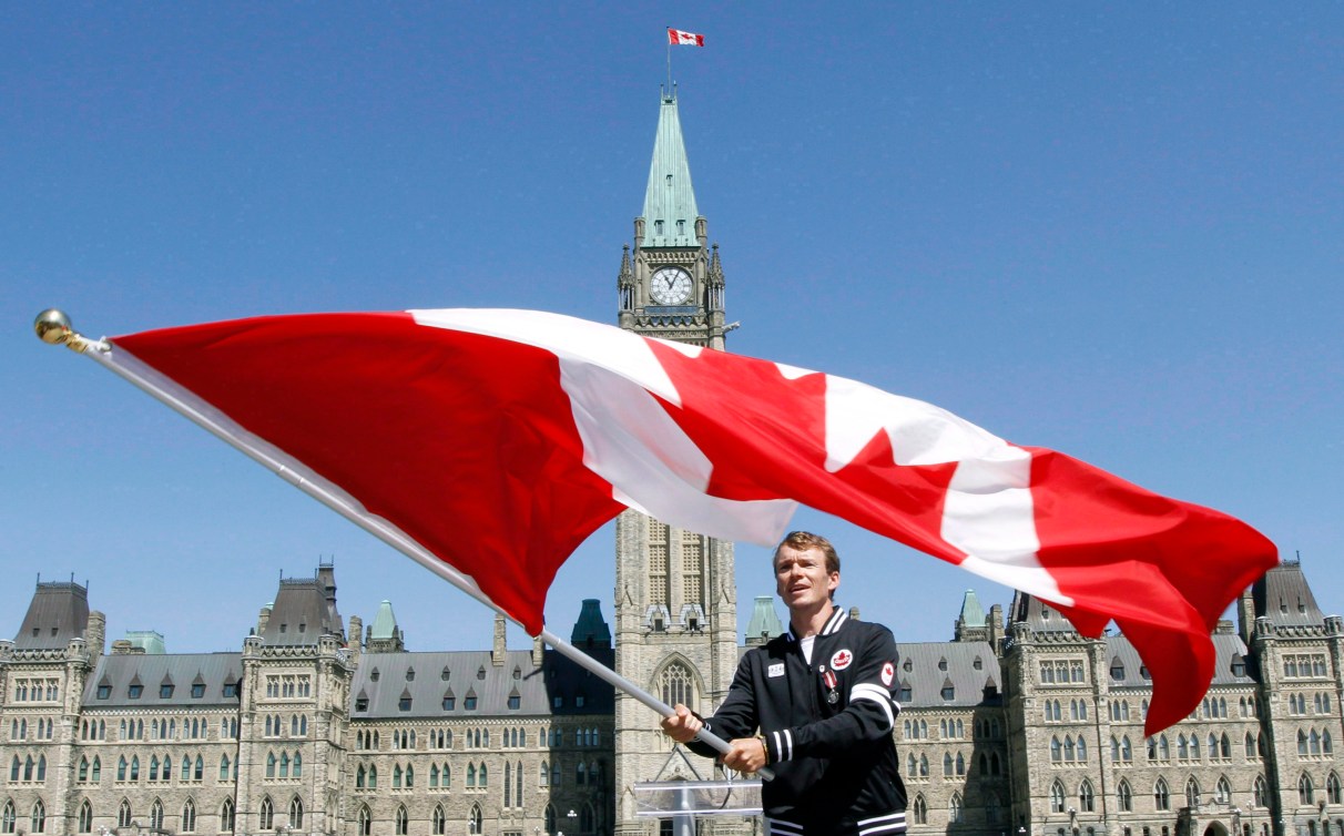 Simon Whitfield waves the Canadian flag on Parliament Hill