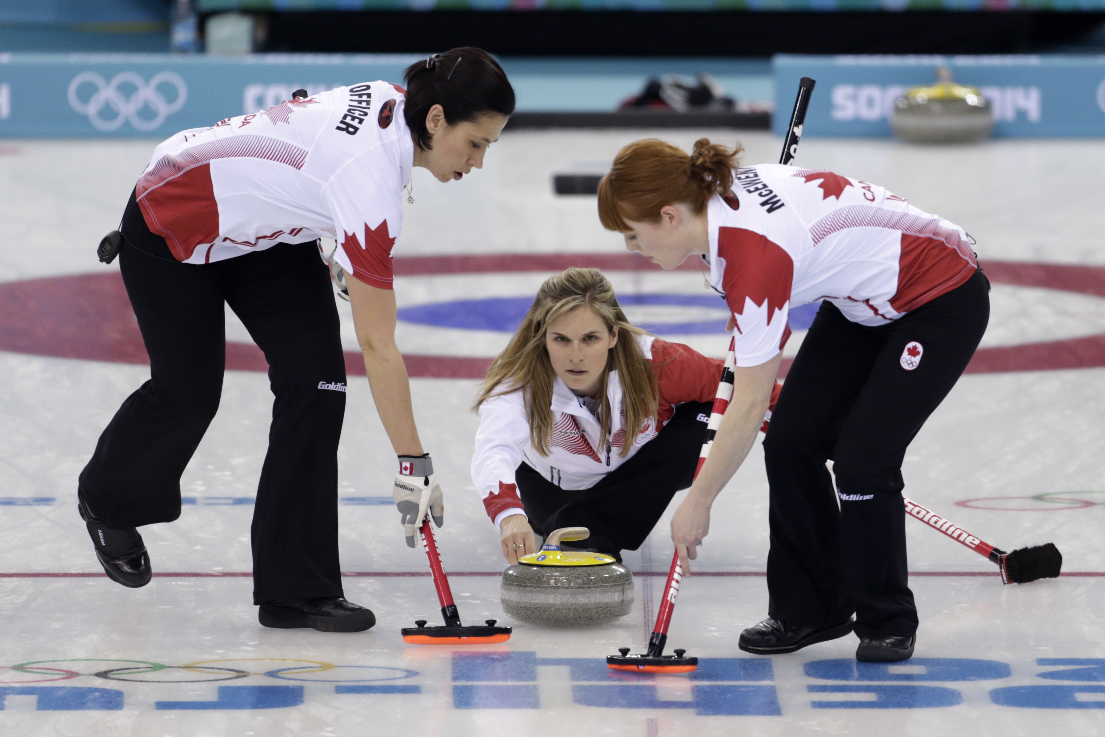 Jennifer Jones throws a stone to be swept by her teammates