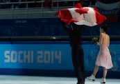 Tessa and Scott celebrate while holding the Canadian flag