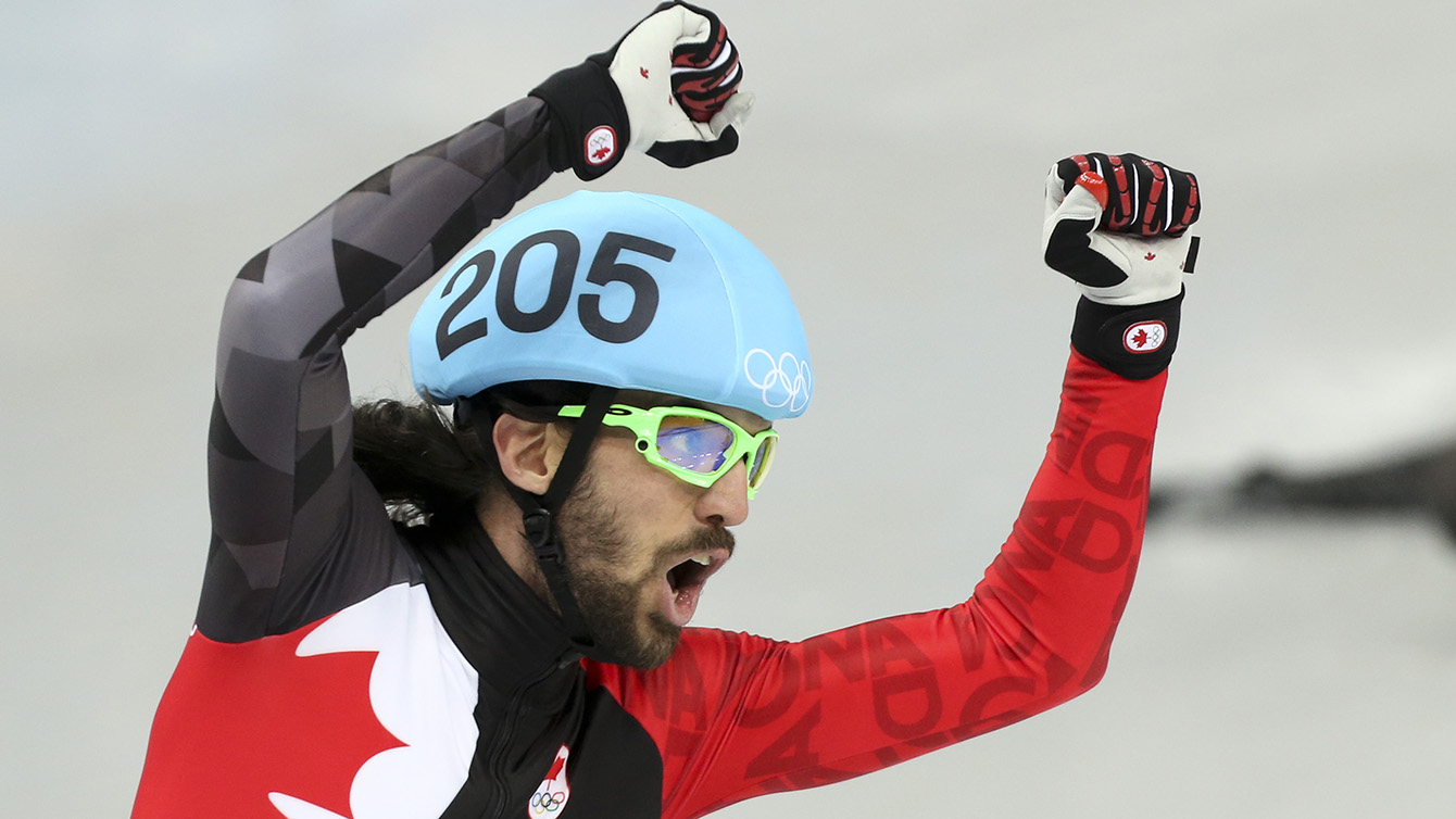 Charles Hamelin celebrates with a Canadian flag after winning 1500m gold.