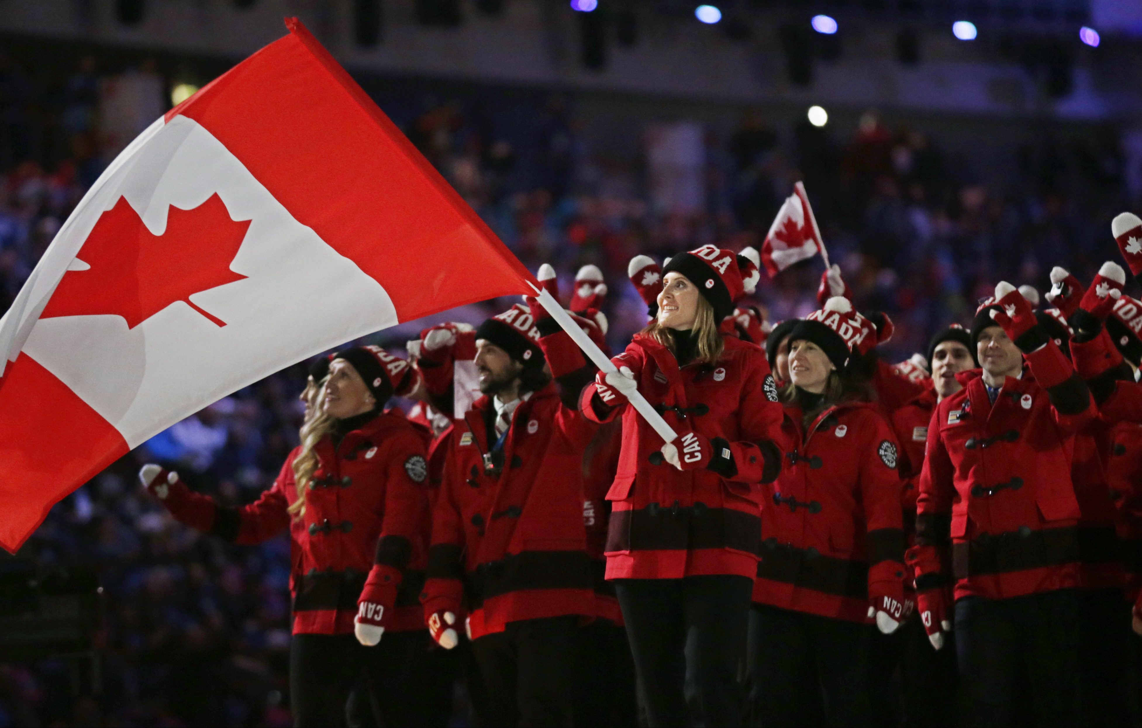 Hayley Wickenheiser of Canada carries her country flag as they arrive during the opening ceremony of the 2014 Winter Olympics in Sochi, Russia, Friday, Feb. 7, 2014. (AP Photo/Matt Dunham)