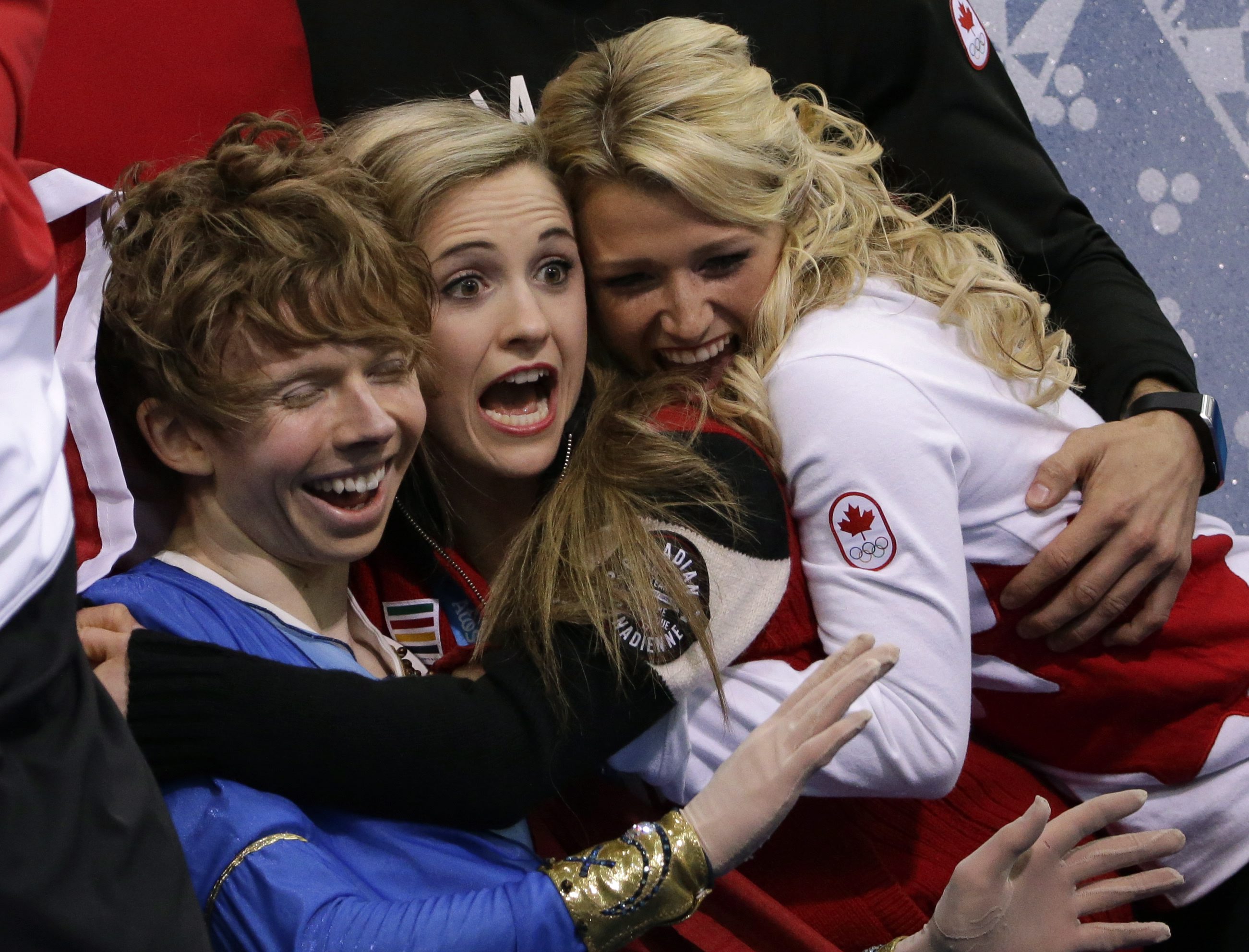 Kevin Reynolds (L) is hugged by teammates Paige Lawrence (centre) and Kirsten Moore-Towers (R) after a performance during the team event.