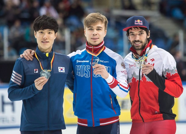 hamelin-1- Winner Semen Elistratov of Russia, center, celebrates beside second placed Han Seungsoo of South Korea, left, and third placed Charles Hamelin of Cananda during the medal ceremony after the men's 1,500 meters final race at the World Cup short track speed skating championship in Dresden, Germany, Sunday, Feb. 8, 2015. (AP Photo/Jens Meyer)