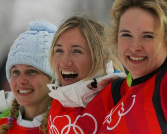 Tanja Frieden of Switzerland, center and gold medallist, American Lindsey Jacobellis, left and silver medallist and Dominique Maltais, right and bronze medallist, react during the flower ceremony of Snowboard cross competition at the Turin 2006 Olympic Winter Games.