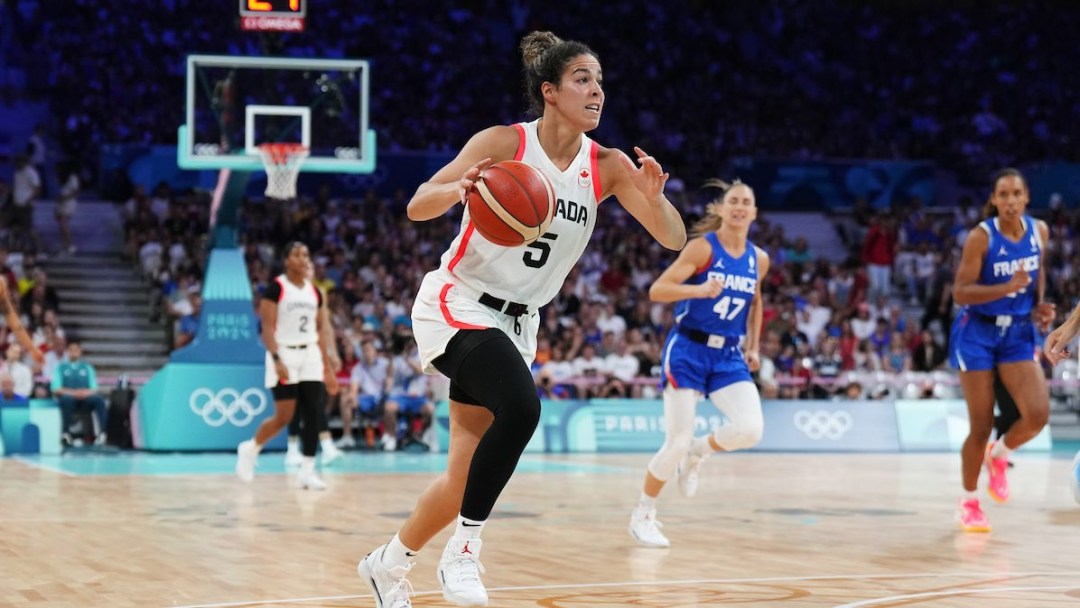 Kia Nurse runs and dribbles while wearing a white jersey