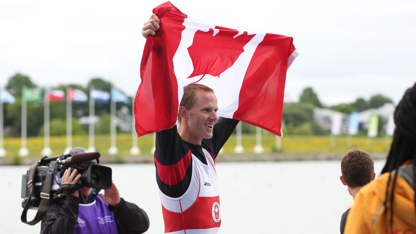 Eric Woelfl holds up the maple leaf after men's lightweight coxless four gold in the Pan Am Games on July 15, 2015.