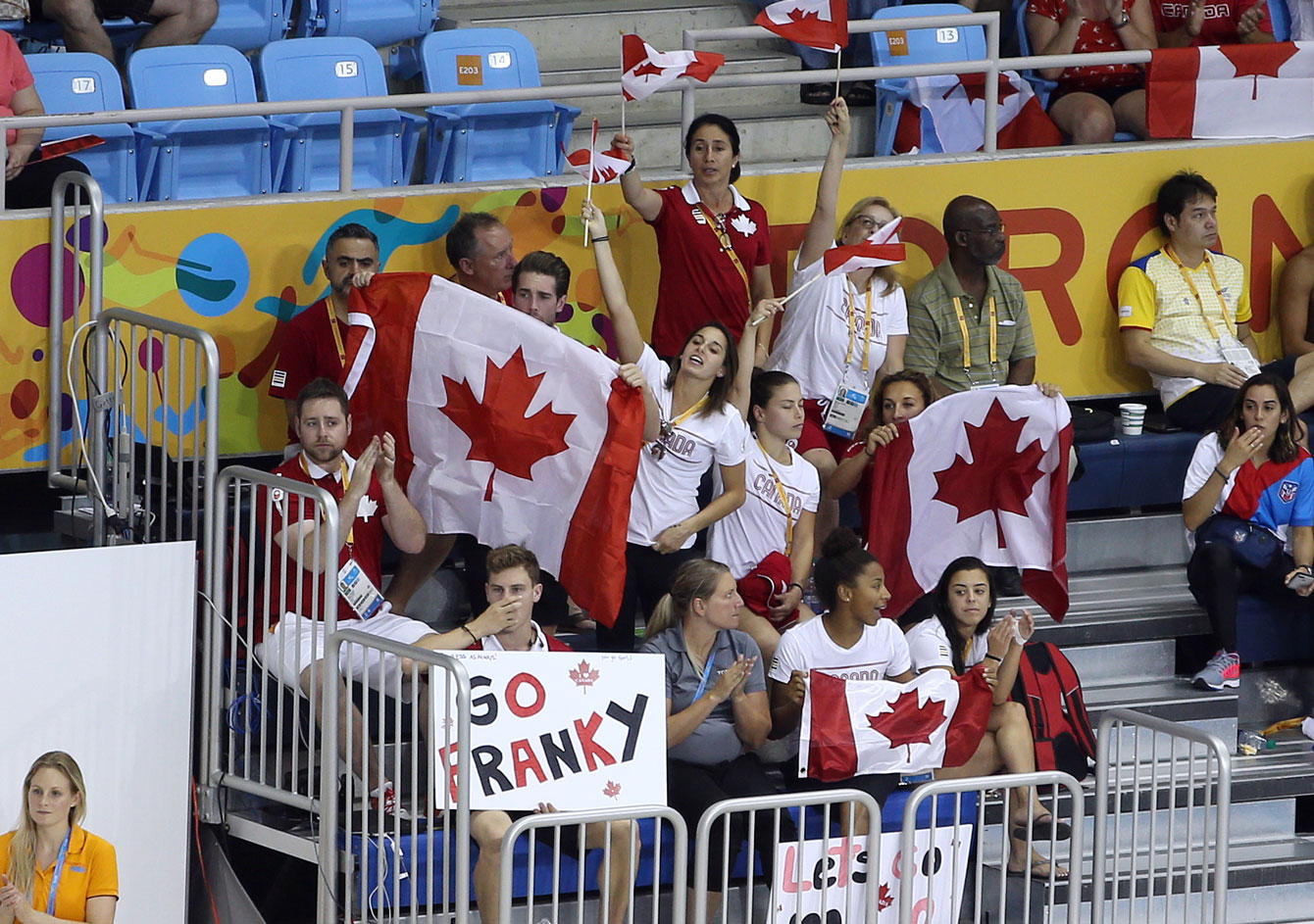 Marcotte (barely visible behind a Canada flag near the right) cheers on diver François Imbeau-Dulac.