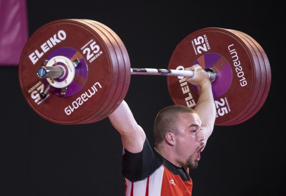 Boady Santavy screams as he lifts weights over head