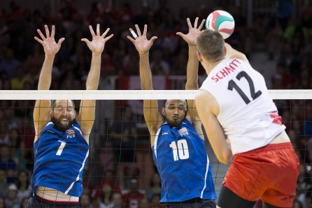 Puerto Rico's Enrique Escalante (left) and Ezequiel Cruz (centre) jump totry and block a spike from Canada's Gavin Schmitt