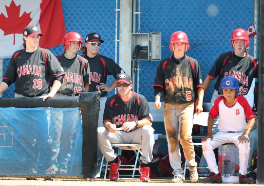 Team Canada manager Andre Lachance sits stoically on a chair watching the ninth inning