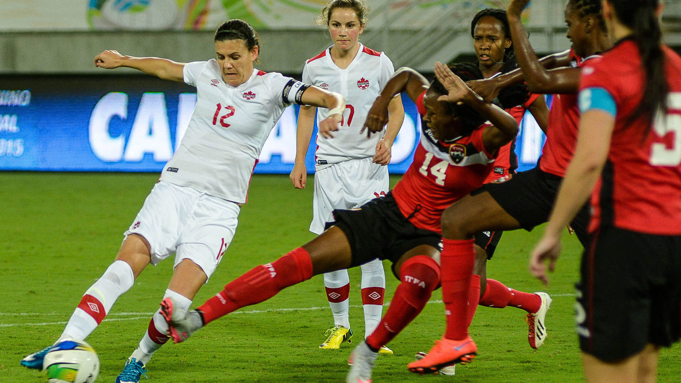 Christine Sinclair (left, in white) sets up to shoot against Trinidad and Tobago on December 13, 2015 at the invitational tournament in Natal. Sinclair scored at the 85th minute to tie Mia Hamm with 158 career goals for second on the all-time list (Photo: Vlademir Alexandre/Allsports).