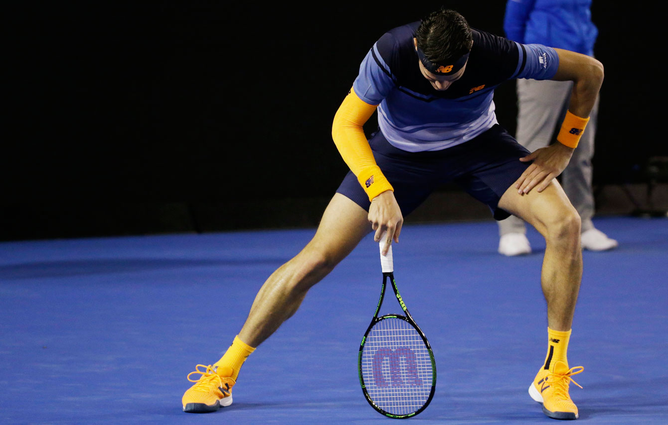Milos Raonic uses his racket to stretch out an injured right leg during his Australian Open semifinal tie on January 29, 2016. 